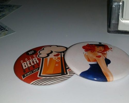 Objet Publicitaire mirroir avec un chope de bière avec un coeur aux couleur rouge, noir et blanc ainsi qu'un pins blanc avec une femme au cheveux orange, une robe bleu et blanche avec une casquette martime et un coeur rouge sur le bras