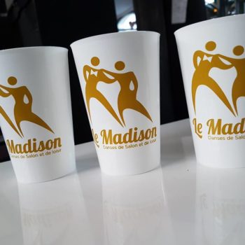 3 verres en plastique blanc, avec sur chaque gobelets un homme et une femme en jaune orangé avec écrit le mot Madison