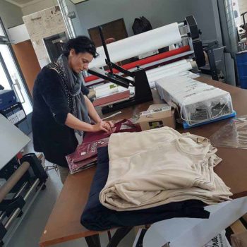 Impression publicitaire, une femme s'occupe des impressions textiles, dans une entreprise de publicité avec des vêtements autour