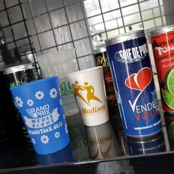 4 canettes de boissons énergisantes et 3 gobelets en plastique personnalisés et situés dans une cuisine