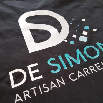 Impression textile sur tee shirt noir, inscrit en blanc et bleu DE SIMON ARTISAN CARRELEUR