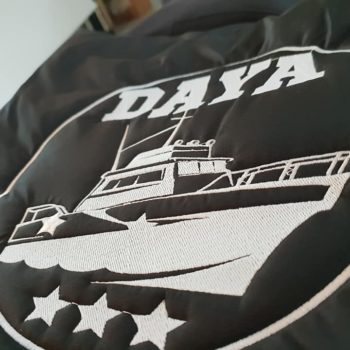 Impression textile, logo day avec une bateau et trois étoiles en blanc sur une doudoune noir