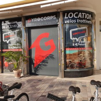 Enseigne et façade aux couleurs blanc, noir et rouge pour des locations et vente de vélos et trotinettes